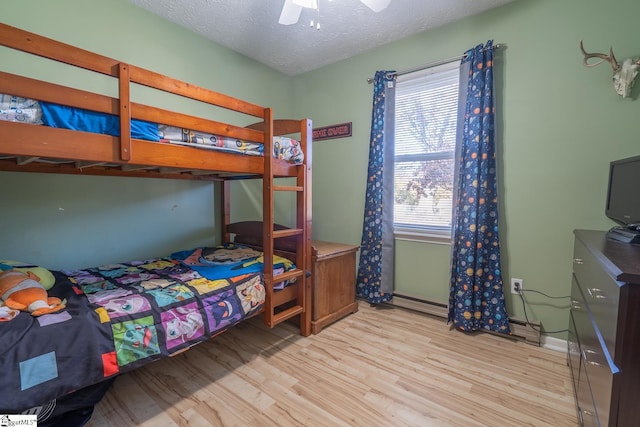 bedroom with ceiling fan, light wood-type flooring, and a textured ceiling