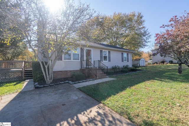 single story home featuring a deck, a shed, and a front yard