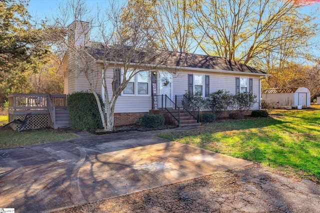 ranch-style home with a wooden deck, a front lawn, and a storage unit