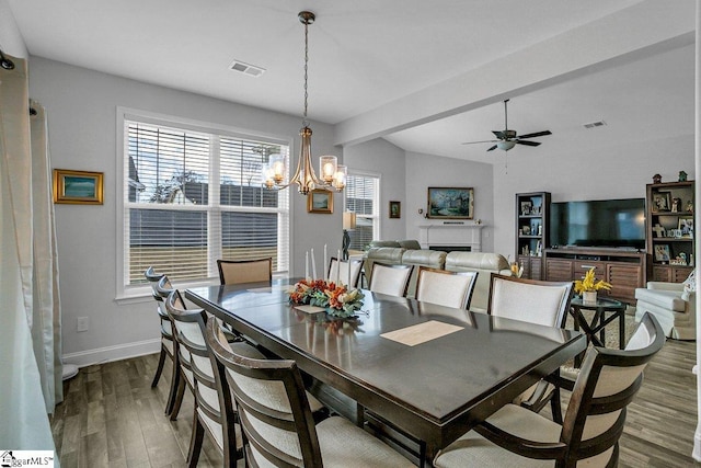 dining area featuring dark hardwood / wood-style flooring, ceiling fan with notable chandelier, and vaulted ceiling