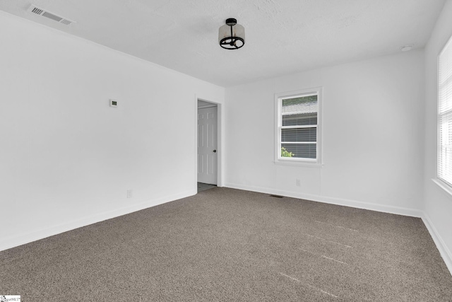 carpeted empty room with a textured ceiling