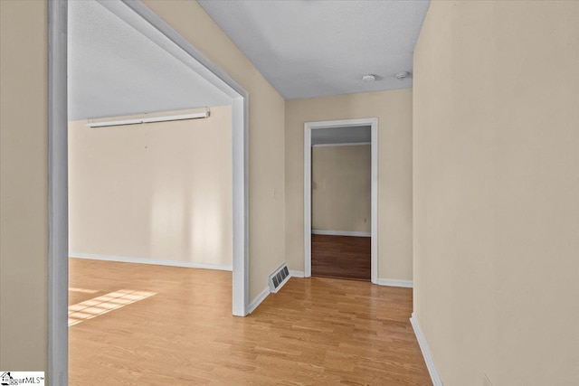 hallway featuring light hardwood / wood-style flooring and a textured ceiling