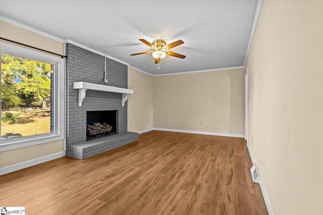 unfurnished living room with ceiling fan, wood-type flooring, ornamental molding, and a brick fireplace