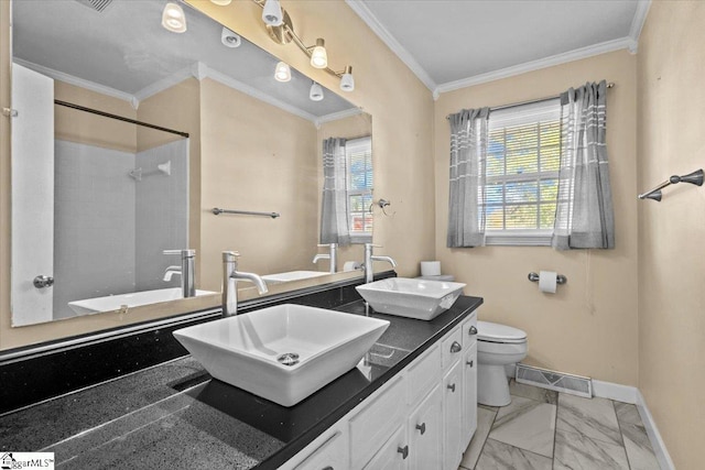 bathroom with a tile shower, crown molding, vanity, and toilet