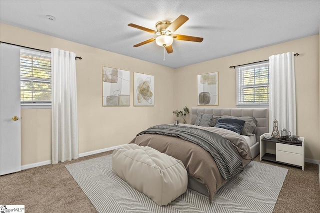 carpeted bedroom with ceiling fan, a textured ceiling, and multiple windows