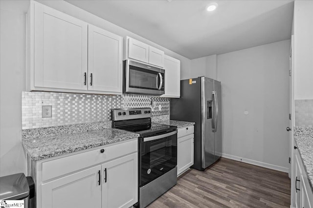 kitchen with white cabinets, stainless steel appliances, light stone countertops, and dark wood-type flooring