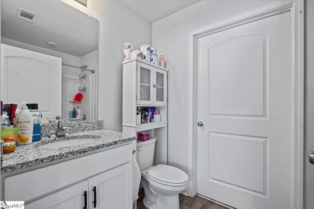 bathroom featuring vanity, toilet, a shower, and wood-type flooring