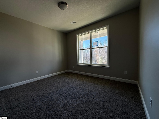 carpeted empty room featuring a textured ceiling