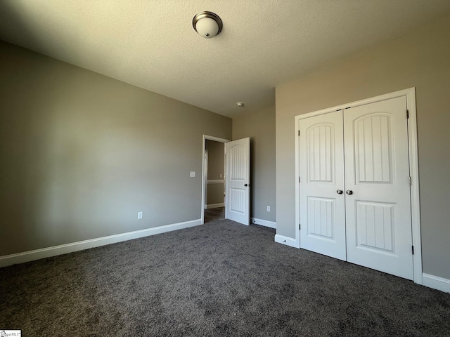 unfurnished bedroom featuring a closet, a textured ceiling, and dark colored carpet