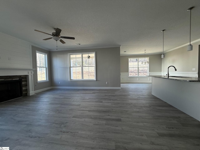 unfurnished living room featuring crown molding, wood-type flooring, sink, and a textured ceiling