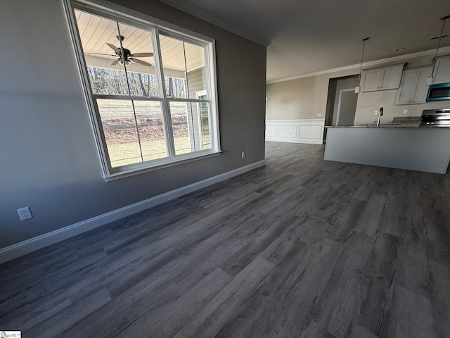 unfurnished living room featuring sink, ornamental molding, dark hardwood / wood-style floors, and ceiling fan