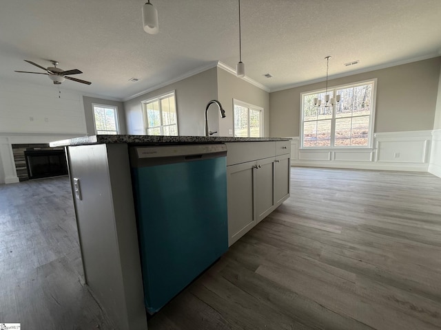 kitchen with pendant lighting, crown molding, dark wood-type flooring, dishwasher, and a center island with sink