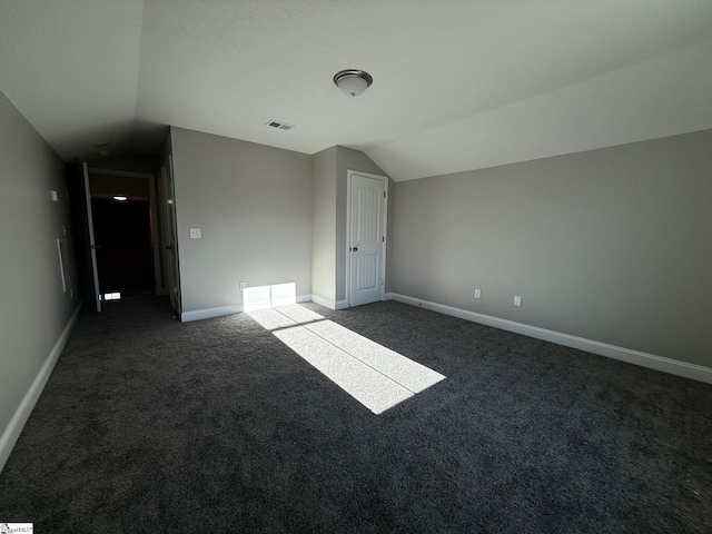 interior space featuring dark carpet and vaulted ceiling