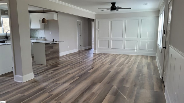 unfurnished living room with ceiling fan, sink, dark wood-type flooring, and ornamental molding