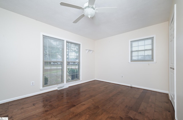 empty room featuring a textured ceiling, a wealth of natural light, ceiling fan, and dark hardwood / wood-style floors