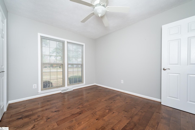 empty room with a textured ceiling, ceiling fan, and dark wood-type flooring