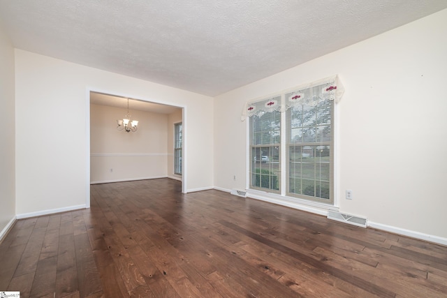 unfurnished room with a chandelier, a textured ceiling, and dark hardwood / wood-style floors