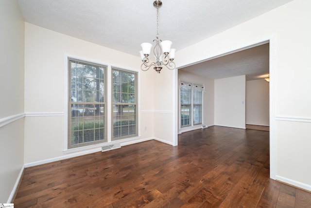 unfurnished dining area with a chandelier and dark hardwood / wood-style flooring