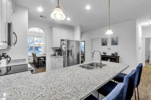 kitchen featuring pendant lighting, sink, light hardwood / wood-style flooring, appliances with stainless steel finishes, and white cabinetry