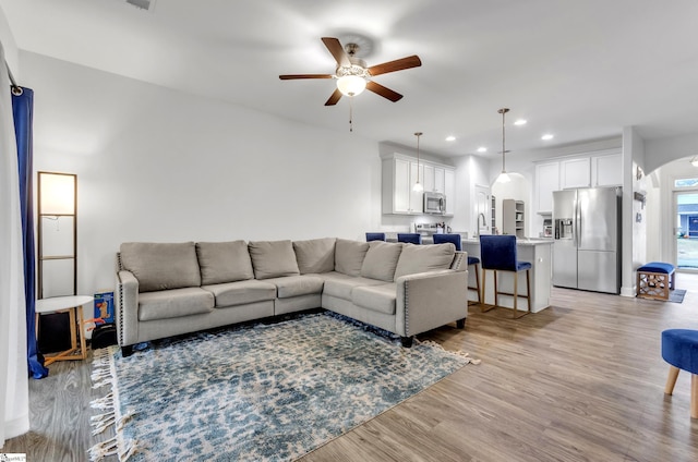 living room with ceiling fan, sink, and light hardwood / wood-style floors