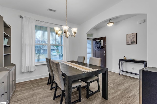 dining area with light wood-type flooring and an inviting chandelier