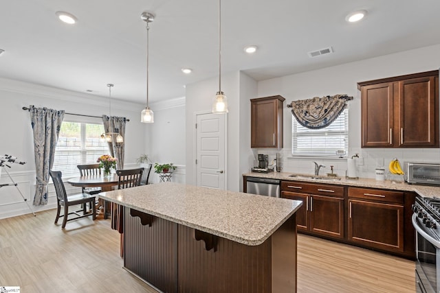 kitchen featuring appliances with stainless steel finishes, backsplash, sink, decorative light fixtures, and a breakfast bar area