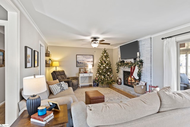 living room featuring ceiling fan, wood-type flooring, ornamental molding, and a brick fireplace