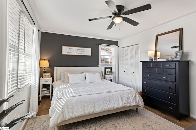 bedroom featuring ceiling fan, ornamental molding, dark wood-type flooring, and a closet