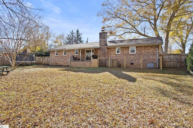 back of property with a yard and a trampoline