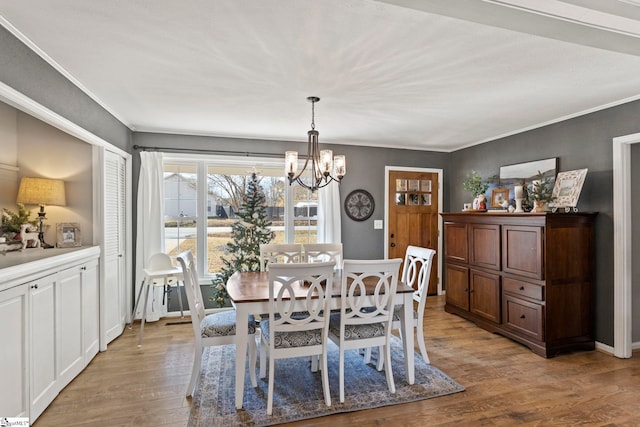 dining space with crown molding, light hardwood / wood-style floors, and an inviting chandelier