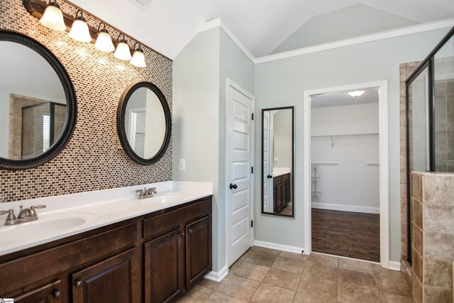 bathroom with vanity, vaulted ceiling, tile patterned flooring, ornamental molding, and walk in shower