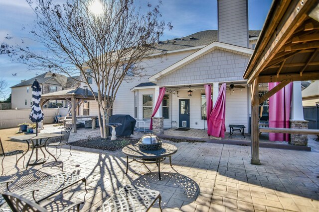 view of patio featuring a gazebo, ceiling fan, and an outdoor fire pit