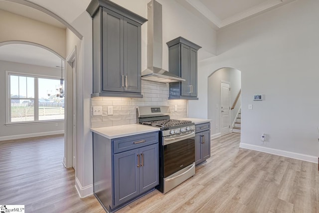 kitchen featuring light hardwood / wood-style floors, gas stove, wall chimney range hood, and tasteful backsplash