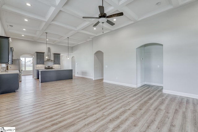 unfurnished living room with coffered ceiling, sink, ceiling fan, beam ceiling, and light hardwood / wood-style floors