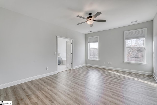 unfurnished bedroom featuring multiple windows, ceiling fan, light hardwood / wood-style flooring, and ensuite bath