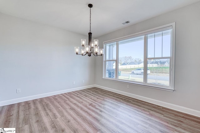 spare room with light hardwood / wood-style floors and a chandelier