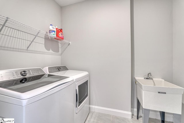 laundry area featuring washing machine and dryer, sink, and light tile patterned floors