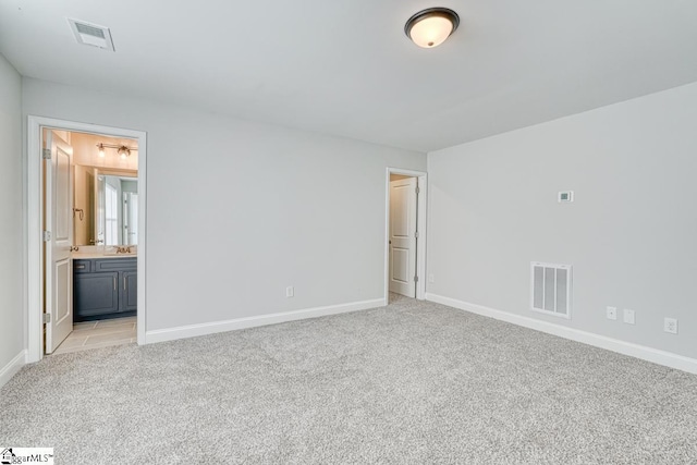 unfurnished bedroom featuring connected bathroom, light colored carpet, and sink