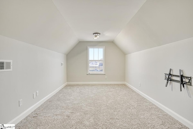 additional living space featuring carpet flooring and vaulted ceiling