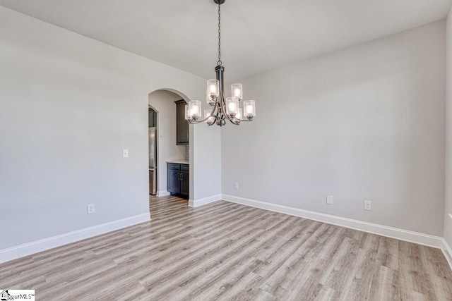 spare room featuring light hardwood / wood-style floors and a notable chandelier