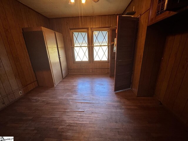 doorway to outside featuring wooden walls, ceiling fan, and dark wood-type flooring