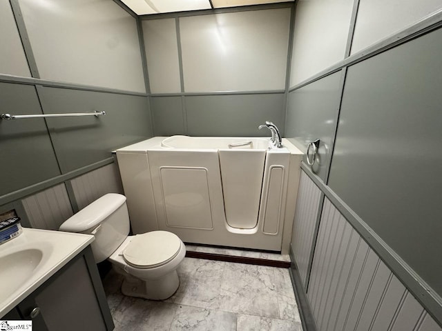 bathroom with a tub to relax in, vanity, and toilet