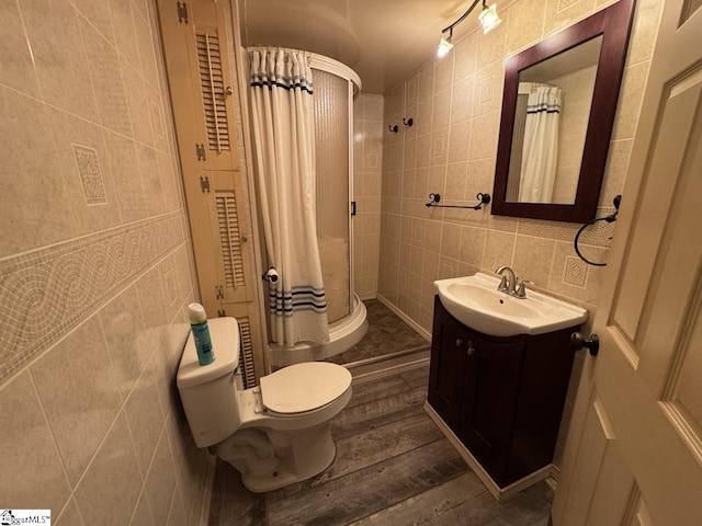 bathroom with a shower with curtain, wood-type flooring, toilet, vanity, and tile walls