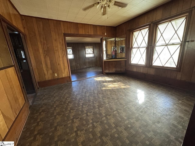 unfurnished room with ceiling fan and wooden walls