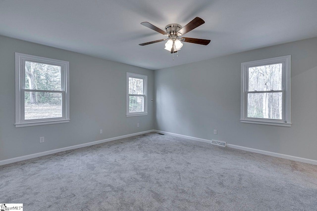 carpeted spare room featuring plenty of natural light and ceiling fan