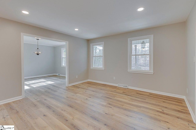 spare room featuring an inviting chandelier, light hardwood / wood-style flooring, and ornamental molding