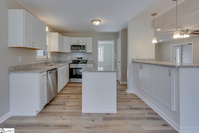 kitchen with white cabinets, sink, hanging light fixtures, kitchen peninsula, and stainless steel appliances