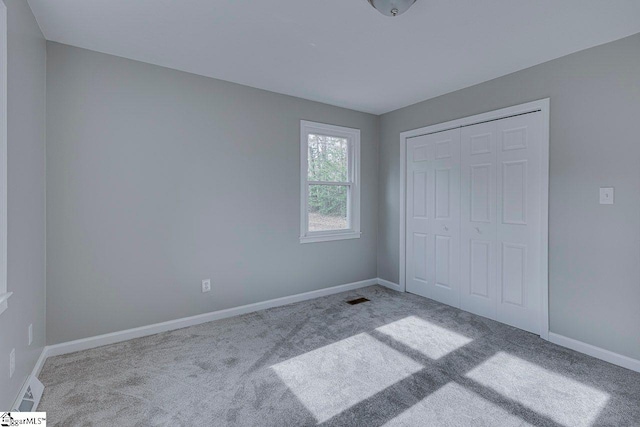 unfurnished bedroom featuring light carpet and a closet