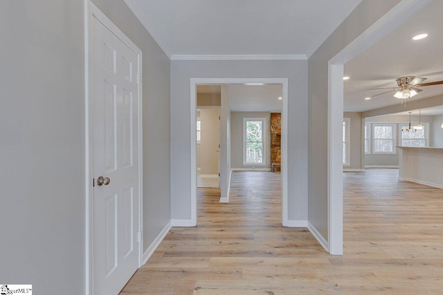 corridor with light wood-type flooring, crown molding, and a notable chandelier