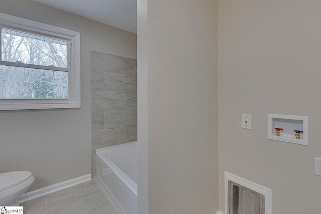 bathroom featuring tile patterned floors, a bathtub, and toilet